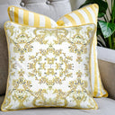 Decorative pillow with floral pattern and another cushion with yellow and white stripes on a grey couch. 