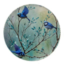 A round ottoman top view, featuring a watercolor-style illustration of three splendid fairy blue birds perched on leafy branches against a soft teal and beige background
