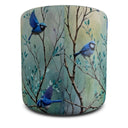 A cylindrical floor pouf or ottoman featuring a printed design of three blue birds perched on branches against a soft, textured teal and beige background.