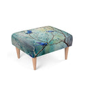 A rectangular upholstered ottoman with a printed design of splendid fairy wren blue birds perched on tree branches, supported by four light wood legs on a white background.