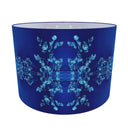 A cobalt blue  drum lampshade featuring a symmetrical, mirrored light blue fractal snowflake pattern on the exterior, shown against a plain white background.