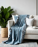 Savanna Blue Velvet Throw styled with blue and white cushions on a white sofa.