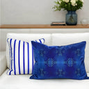 Cobalt blue velvet cushion and cobalt and white striped cushion paired and  styled on a white sofa. 