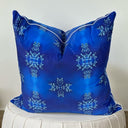 Cobalt blue velvet cushion  with white piping on a white ottoman. 