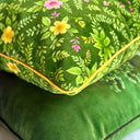 Green floral-patterned velvet cushion with yellow piping. Up close view. 