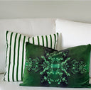 Two decorative throw pillows on a white sofa: one green and white vertically striped pillow, and one emerald  green pillow with a large glowing green fractal snowflake design.
