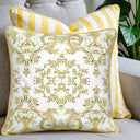 Decorative pillow with floral pattern and another cushion with yellow and white stripes on a grey couch. 
