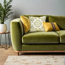 Yellow and white patterned cushion with yellow piping, styled on an olive green sofa. 
