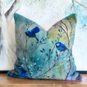 Teal Decorative pillow with splendid Fairy  blue bird design on a wooden surface. 