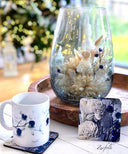 Blue Evon Coasters , 10cm x10 cm .set of 4 (Styling) with a coffee cup on a white coffee table 